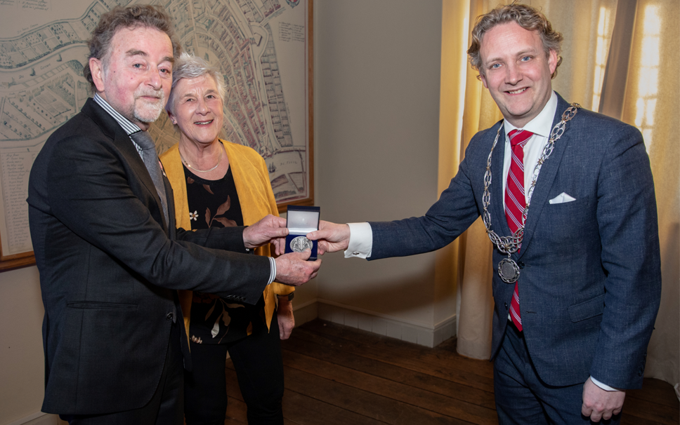 Foto: Astrid den Haan- Burgemeester Pieter Verhoeven overhandigt de zilveren erepenning aan Piet Zuijdwijk vergezeld door zijn vrouw.
