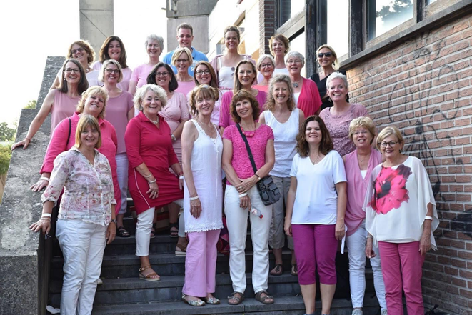 Mixed Voices groep op de trappen van stadhuis Gouda gekleed in wit en roze