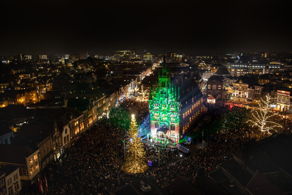 The countdown has just ended and the lights in the tree are lit. The City Hall is illuminated by candlight in the windows.