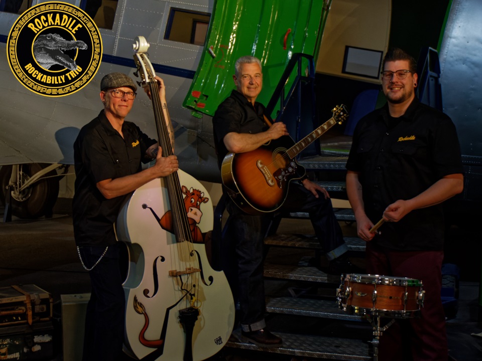 Drie heren onder een festival tent met hun instrumenten