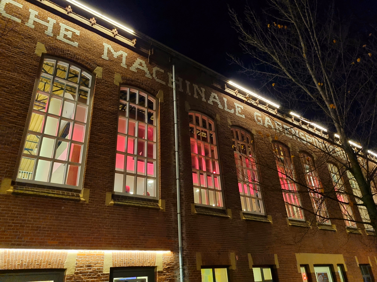 Voorgevel van Garenspinnerij met groot aantal fietsen ervoor en rechts bomen